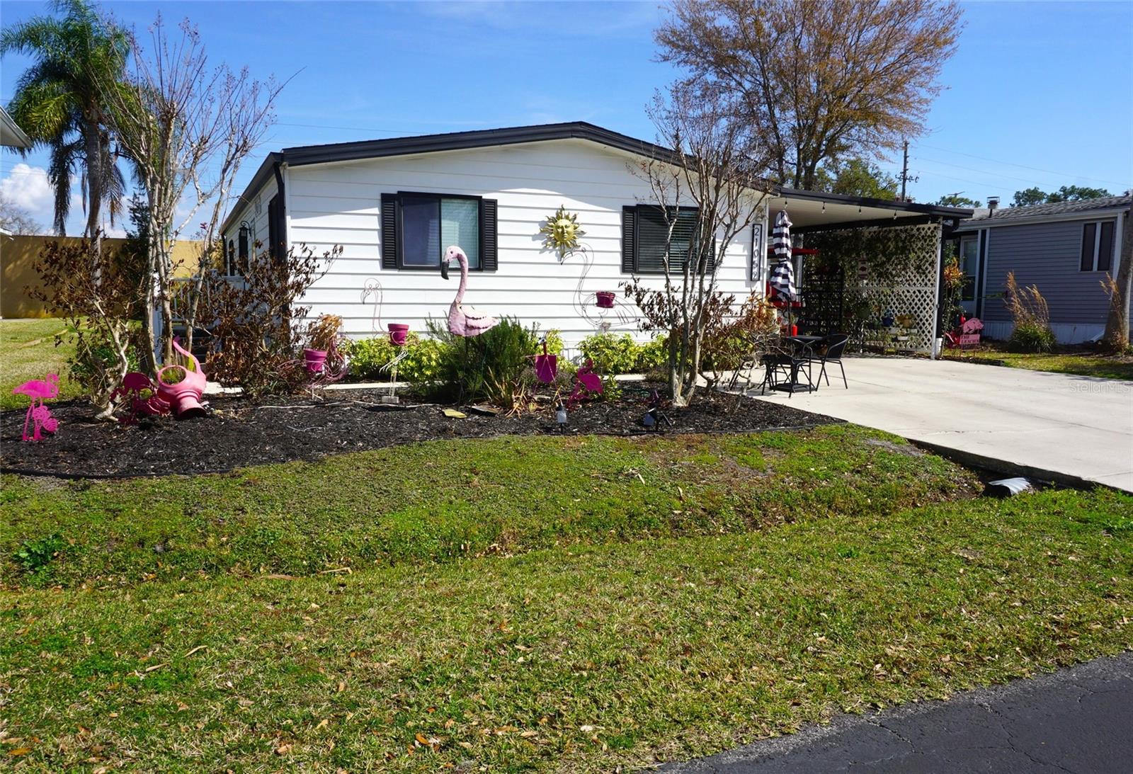 Updated Single-Family home located in the gated nudist/clothing-optional community of Paradise Lakes. Open concept split bedroom floorplan with neutral colors and wood laminate flooring throughout. The remodeled kitchen features newer cabinets, granite counters, smooth-top induction range, 3-door refrigerator, dishwasher, disposal, built-in microwave, and breakfast bar. Spacious primary ensuite bedroom with granite top vanity, walk-in shower, linen storage, and walk-in closet. Two secondary bedrooms with mirror closet doors are ideal for guests or an office. Full second bath with granite vanity top and tub/shower combination. Light and bright living room is ideal for entertaining. Spread out in the enclosed 264 sq ft flex/bonus room with new frames/screens, bar, and plumbed exhaust heating/cooling unit. New AC in 2025, newer roof, plumbing, appliances, flooring. This lovely home has an electric/solar hybrid water heater, attached shed/workshop with tons of extra storage, grassy fenced yard with paver patio, garden beds, and water softener system. Inside laundry room with full-size washer/dryer. Off-street parking with concrete driveway and covered carport. Buyer is responsible for verifying all information, details and dimensions. Condo association approval of Buyer is required including application, fee, background check, orientation, and membership in a recognized nudist organization. Optional membership to Paradise Lakes Resort is not included in monthly condo association fee.