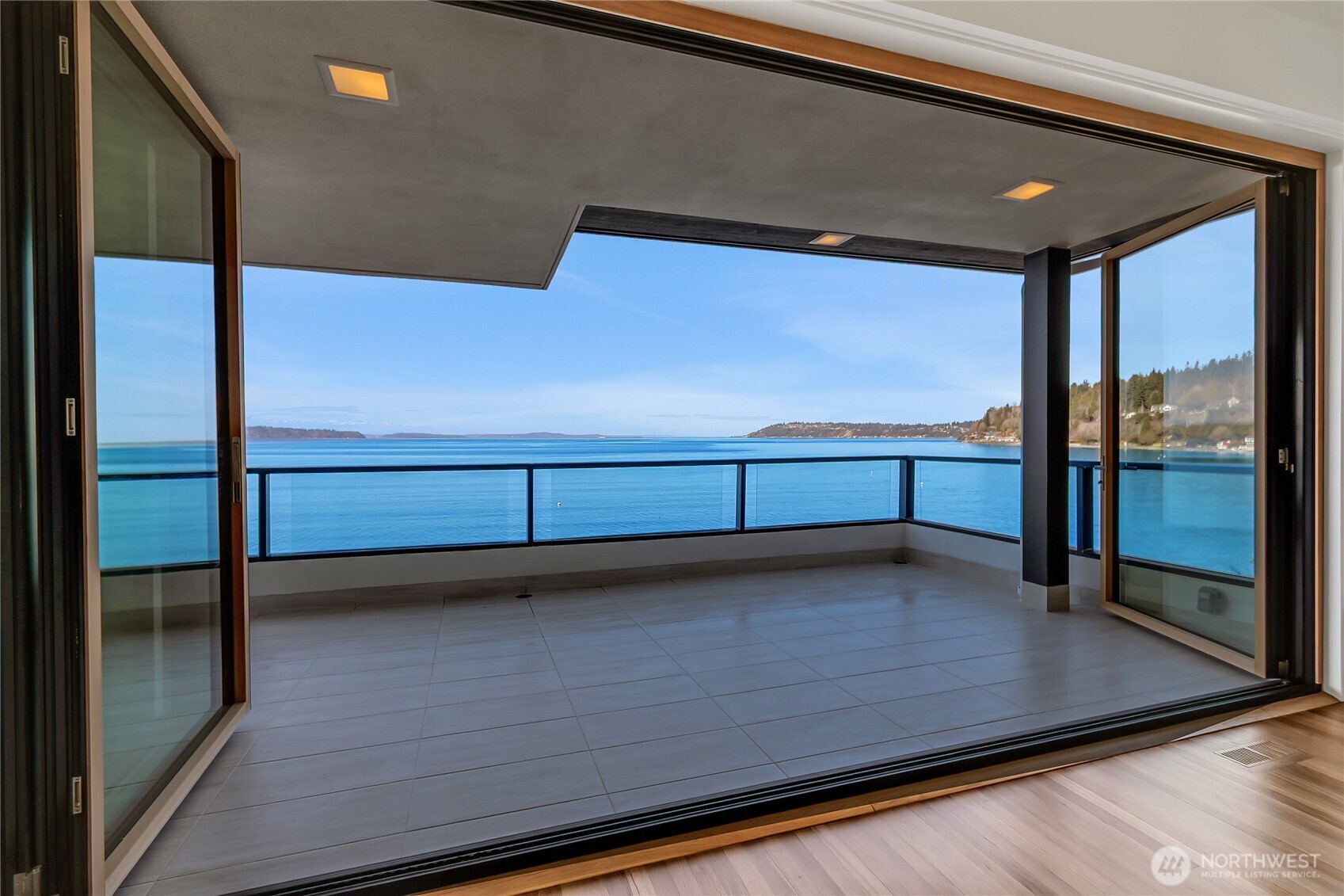 Rare low-bank waterfront opportunity with 122 feet of sandy beach and panoramic Puget Sound views. Spanning 7,050 square feet, this five-bedroom, five-bath residence offers two primary suites across three thoughtfully designed levels. Enjoy spectacular sunsets from nearly every room. The chef’s kitchen features custom cabinetry, quartzite countertops and premium finishes, while spa-inspired bathrooms provide a refined retreat. Expansive walls of glass fill the home with natural light and frame the ever-changing waterfront scenery. A dramatic four-panel LaCantina bifold door system opens the living space to the waterfront terrace, creating effortless indoor-outdoor living. Designed for comfort, entertaining and connection to the water, this exceptional residence is a true Pacific Northwest sanctuary.