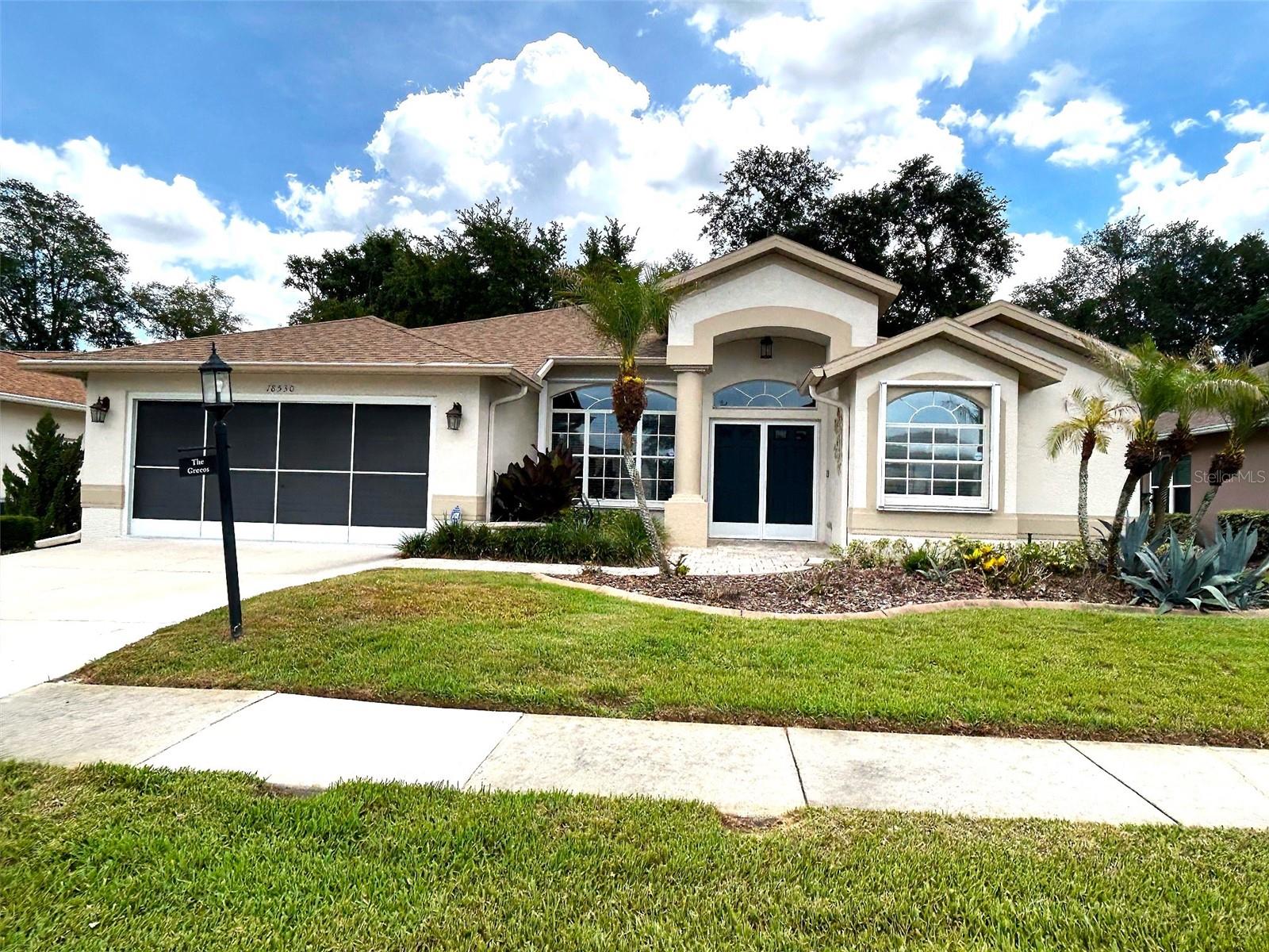 All the special features are apparent right from the paver walkway up to the gracious double door entrance. Just inside, you are met with vinyl plank flooring to set off all the decor. The living room is really a great room incorporating the dining space as well. Moving through to the kitchen area, you have a nook with decorative seating. The appliances include a double oven and cooktop, with a very large pantry off the kitchen. Open to the kitchen, there is a large family room with sliders to the expansive lanai.  The lanai has been enclosed and has access from the main bedroom. The floor plan is a split bedroom plan with the main bedroom and ensuite bath, separate from the guest bedroom, office, and bath. The rear yard is its own private haven, lush, green, and beautiful.  A new roof was installed in 2025, and the home is protected by an ADT security system. The home was remediated in 2012 to provide the securist of foundations, documents available upon request. Most lighting, mirrors, and fixtures have been updated, including crown molding throughout. The washer, dryer, and utility sink are located in the expanded garage, which has tile flooring. There is a front door screen as well as garage screening. All furnishings are available. A new buyer is going to love living in Heritage Pines, with the private 18-hole golf course, pickleball courts, lighted tennis courts, and, not to mention, the excellent dining and entertainment available most nights of the week.  What a great place to live!!