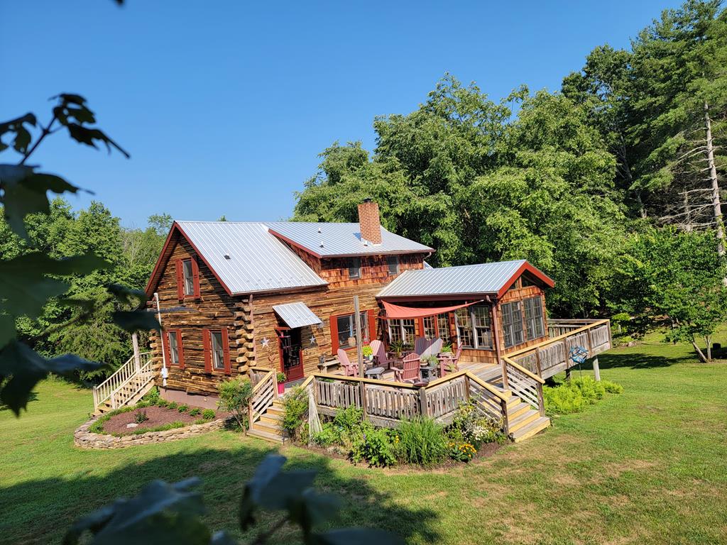 A Hidden Log Home Retreat on 53.18 Acres in Beautiful Grayson County, Virginia  Some properties simply have a feeling that can't be described—you have to experience it. From the moment you turn onto the private drive, you'll know you've found something truly special. Nestled deep within 53.18 breathtaking acres, this charming log home has been thoughtfully expanded and enhanced over the years, blending timeless rustic character with the comfort and warmth of a true family home. Step inside and you'll immediately feel welcomed by its inviting atmosphere. Every room radiates comfort, and you'll feel right at home from the moment you walk through the door. The scenic drive to the home is an experience in itself. Drive alongside a meandering creek through rolling grasslands where numerous bird species can be seen throughout the seasons. Towering rock formations line portions of the driveway, creating a dramatic entrance before the home comes into view, perfectly positioned with a beautiful deck overlooking its peaceful surroundings. The property offers the ideal balance of open pasture (approx 13 acres) and mature woodlands, with fencing already in place for horses or livestock. A gently rolling yard provides plenty of room for children, pets, and outdoor gatherings, while the surrounding acreage offers endless opportunities to explore, hunt, hike, or simply enjoy nature. Adding even more charm is a unique historic barn full of character, complete with a spacious loft that speaks to the property's rich heritage and offers endless possibilities for storage, hobbies, or restoration. Inside, the cozy sunroom quickly becomes a favorite gathering place, providing panoramic views of the surrounding countryside through nearly every window. Whether enjoying your morning coffee, watching wildlife, or taking in the changing seasons, every view reminds you why properties like this are so rare.
