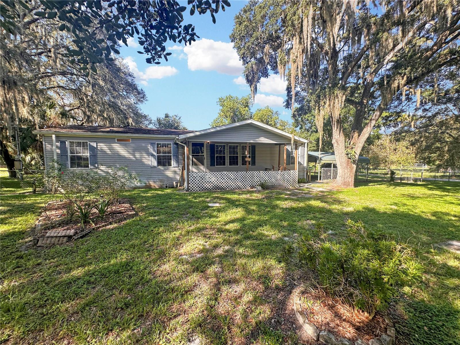 Room to spread out, space for the toys, bring the boat, trailer, vehicles, animals, and over an acre beneath beautiful mature Florida oaks! Welcome to 10700 Tami Trail, a 3-bedroom, 2-bath home situated on approximately 1.1 acres with an impressive amount of covered parking, workshop and storage space. Built in 2006, the 1,512-square-foot home features an open living and dining area, vinyl flooring and a spacious kitchen with abundant wood cabinetry, tile backsplash, center island and breakfast bar overlooking the main living space. An additional 108-square-foot office/bonus room provides flexible space for working from home, hobbies or extra storage. The interior laundry room offers additional cabinetry and shelving. Outside is where this property really stands apart. The fenced front yard is shaded by large, beautiful oak trees, while two covered carports and two storage sheds provide plenty of additional utility. The standout feature is the large metal building with concrete floors, electric, storage shelving and two roll-up doors creating a convenient drive-through setup—ideal for boats, trailers, vehicles, equipment or a dedicated workshop. With 1.1 acres and plenty of room to park, work and enjoy the outdoors, this property offers the space and versatility that can be hard to find.