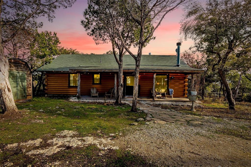 Escape to your own private retreat in this secluded log cabin perched atop Chalk Mountain! Set on over 11 acres of partially fenced land, this property offers unmatched privacy, tranquility, and breathtaking views of the surrounding countryside. Inside, the open concept layout showcases vaulted ceilings, a welcoming kitchen, and a cozy living area perfect for gathering. Durable concrete floors throughout provide easy care and low maintenance. The primary suite features a private bath with a deep soaking tub, ideal for unwinding after a day outdoors. An additional bedroom and full bath ensure comfort for family or guests. Step outside to the expansive covered porch and enjoy watching deer, birds, and other wildlife in their natural setting. The property also includes two storage buildings, a tornado shelter, and a dependable well with a Strata care filter system. Located just minutes from Fossil Rim Wildlife Center, Dinosaur Valley State Park, and Rough Creek Lodge, this home offers the perfect balance of seclusion and convenience. Whether you’re looking for full time country living or a weekend escape, you’ll also appreciate being within easy reach of Stephenville for shopping and amenities. Come experience the beauty, peace, and charm of country living on Chalk Mountain!
This home has also been a successful Airbnb!