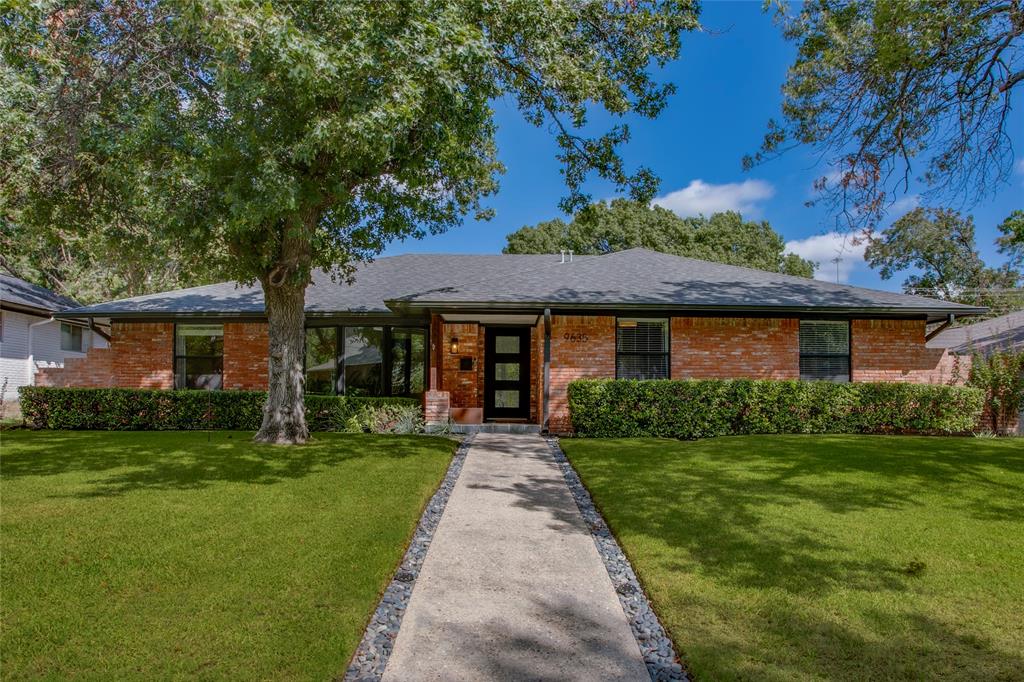 A sweeping shade tree, classic brick exterior and a welcoming front porch set the tone for this Lake Highlands ranch. Inside, warm wood floors and expansive windows complement a versatile layout with four bedrooms, two living areas and a separate dining room.The front living room’s broad bay window brings in beautiful natural light and leafy views, while the adjoining dining room is ready for everything from casual dinners to a full holiday table. Beyond, a vaulted, beamed ceiling gives the second living area an airy feel, with a painted brick fireplace and a built-in bar featuring floating wood shelves and a herringbone tile backsplash.The kitchen pairs abundant white cabinetry and granite counters with a professional Bertazzoni gas range, an additional wall oven and stainless appliances. A sunny breakfast nook provides a spot for morning coffee, and a separate laundry room adds storage and everyday convenience.The oversized primary suite offers room for a sitting area, a generous walk-in closet and an ensuite bath featuring dual sinks and a glass-enclosed shower. Three additional bedrooms provide flexibility for guests, work or creative pursuits.Sliding glass doors connect the main living area to a patio beneath shade sails and string lights. A mature shade tree and spacious fenced lawn create an inviting backyard for outdoor meals, play and relaxed evenings at home.
