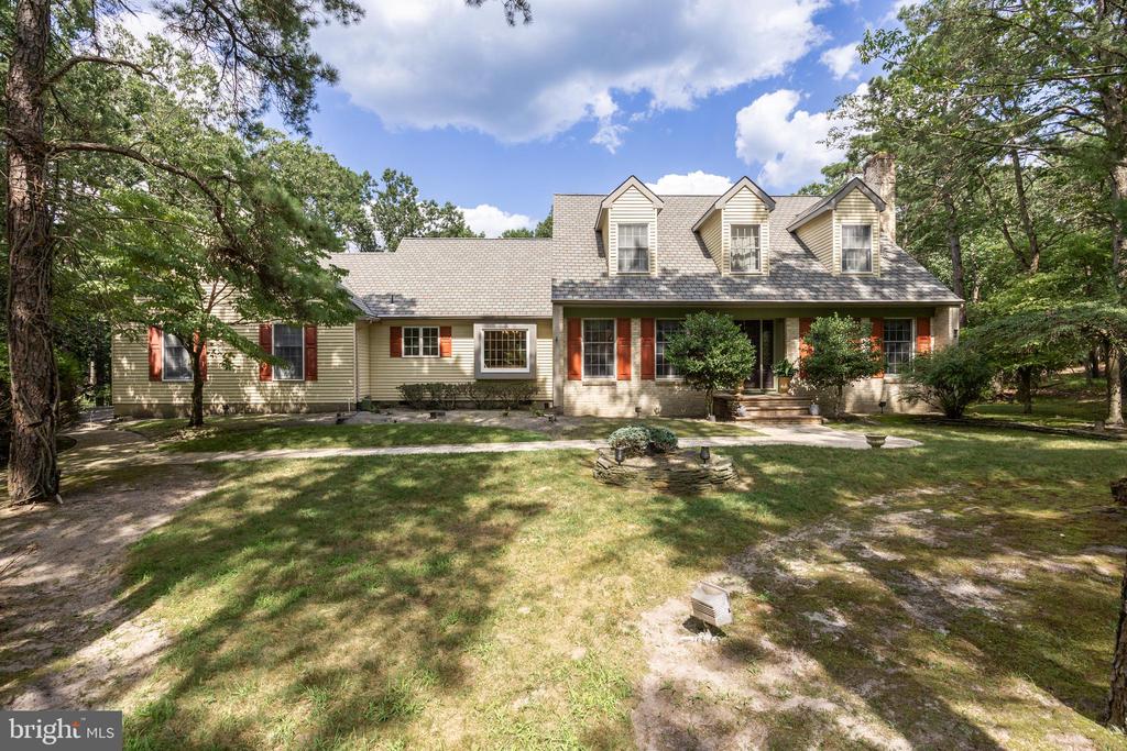 Set on 1+ acre wooded lot, this timeless New England-style Cape offers charm, exceptional private outdoor living and a first floor primary which is a rare find.  A free-form gunite pool with stone waterfall surrounded by mature trees, creates a serene backyard retreat, viewed from a large custom deck—perfect for entertaining or your quiet morning coffee.  Inside, thoughtfully defined spaces balance connection and privacy, a refreshing alternative to open concept, and functions better long term.  It features hardwood flooring throughout most of the first floor, a welcoming center hall, and spacious formal living and dining rooms. The expansive family room at the rear of the home includes custom built-in cabinetry and wine bar, as well as one of the home's two fireplaces, and overlooks the backyard and deck. The updated eat-in kitchen is a chef’s dream, featuring updated maple cabinetry, a cozy bay window with seating, granite countertops, travertine marble backsplash, and Italian tile wood-look flooring for a warm, contemporary touch. Watch hummingbirds from the first floor primary suite and enjoy the changing seasons. It is a true sanctuary with a walk-in closet and a spa-inspired master bathroom. Highlights include Carrera marble vanity tops, striking free-form vessel bowl sinks, a frameless glass shower, whirlpool tub, and vaulted ceilings with skylights. Upstairs offers three oversized bedrooms and an updated full bath. Throughout the home, you'll appreciate the attention to detail, custom built-ins, upgraded millwork, and the timeless character that defines this unique property. Additional amenities:  Septic Certified (2025) Certification uploaded. New HVAC (2024), New hot water heater (2024), New pool motor (2024), Deck refinished (2023), Anderson windows, CertainTeed “slate-look” 50 yr roof completes the picture, enhancing the home’s curb appeal and durability. Homes like this don’t come along often.  Make it yours!