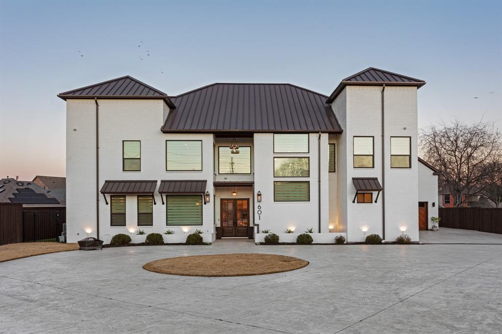 This exceptional custom estate blends architectural sophistication, refined finishes, and modern smart-home technology across a stunning main residence and an expansive guest home. A circular stamped-concrete drive, covered entries, and eight-foot cedar fencing create striking curb appeal and privacy from the moment you arrive. Inside, hand-laid 5-inch white oak hardwoods, soaring 28-foot vaulted ceilings, and an Austin White stone gas fireplace set the tone for elevated living. Entertain effortlessly with a quartz-topped bar beneath the back staircase, a statement dining room with shiplap accent wall and Taj Majal quartzite coffee bar, and a chef’s kitchen featuring an oversized Cristallo quartzite island, pot filler, and professional-grade appliances. The spa-inspired owner’s retreat offers marble finishes, a rainfall shower, and a custom walk-in closet with center island, while secondary bedrooms provide private baths, walk-in closets, and 10-foot ceilings. A private theater with concealed entry, dedicated office, and designer laundry room add both luxury and functionality. Outdoors, enjoy a professionally designed backyard with premium turf, basketball court, and a covered, ventilated porch complete with dual gas grills, fire pit, and wood-burning chimney, prepped for a future luxury pool. The approximately 2,202 sq. ft. guest house with separate utilities is ideal for multigenerational living or entertaining. Built for performance and peace of mind, the home features an engineered slab foundation, closed-cell foam insulation, hail-resistant metal roof, dual high-efficiency zoned HVAC systems, whole-property Generac generator, tankless water heaters, smart irrigation, EV-ready oversized garage, and integrated smart security. A rare opportunity to own a truly distinguished, resort-style estate where timeless design meets modern innovation.