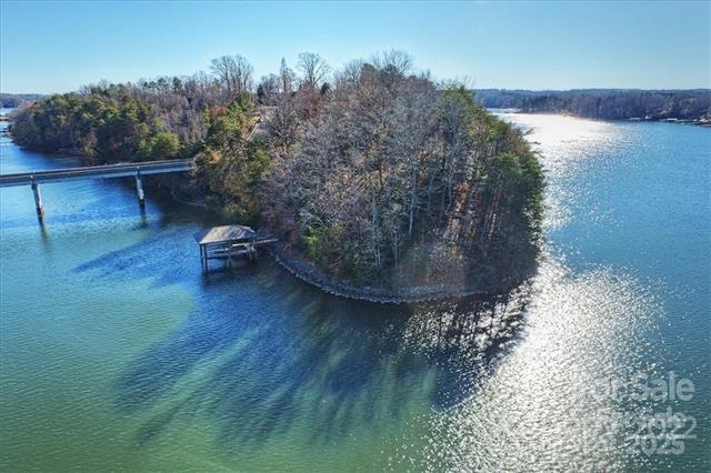Sellers may consider TRADE in Lake Norman - Charlotte area with short term owner finance...Breathtaking point lot with panoramic view of Lake Norman! Marvel at sunrise and sunsets from this unbelievable property "possibly" DIVIDABLE... 500' of rip-rapped shoreline, 12x30 covered boat-slip, 7000 lb boat lift with generator and controls. Bridge connects access to the private island. Perfectly sloped for a basement estate home. Enjoy community clubhouse, pool and tennis courts in this gated neighborhood. Gates open from 7am-7pm code required after hours... call list agent. Lake Norman State Park just minutes away to bike and hike!