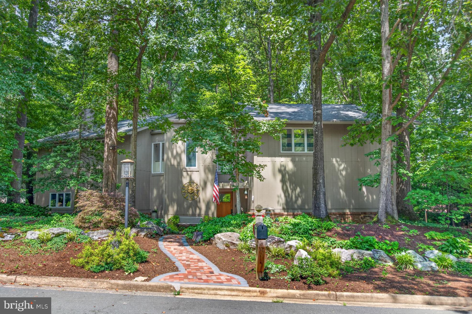Some homes sit on their lots. This one was designed to become part of its setting. Built by noted Reston builder Warren Katz, 11424 Purple Beech Drive is a distinctive contemporary tucked beneath a canopy of mature trees, with seasonal views of Lake Thoreau, neighborhood lake access and a remarkably walkable South Reston location. The unconventional, angular floor plan reflects the character of Katz-built homes: contemporary lines, abundant natural light and rooms thoughtfully oriented toward the surrounding landscape. A welcoming foyer introduces the main level, where the kitchen, breakfast room, dining room and living room flow together across one side of the home. At the center, a circular free-standing fireplace creates a shared hearth between the living and dining spaces, and the background brick wall creates an efficient heat sink.  Redesigned with cooking and entertaining in mind, the custom kitchen is both striking and exceptionally functional. Silestone countertops, hardwood flooring, and extensive cabinetry surround a large stainless steel farmhouse sink, secondary prep sink, and two disposals.  Appliances include a Sub-Zero cabinet-depth refrigerator, DIVA induction cooktop with Wolf downdraft ventilation, a new built-in double/convection/microwave oven, a warming drawer, a steam oven, and a refrigerator. Pull-out shelving, specialized spice storage, a pantry with an Elfa organization system and professionally painted cabinetry complete the space. The opposite side of the main level includes a private office, powder room, oversized coat and storage closet with an Elfa system, and access to the two-car garage. Pocket doors, recessed lighting, hardwood flooring, custom built-ins, and Andersen windows appear throughout the house.Upstairs, the spacious primary suite is complemented by two additional bedrooms, including one with an en-suite bath and a large cedar-lined closet. The renovated primary bath offers the feel of a private spa, with heated tile floors, a skylight, custom teak dual-sink vanity and cabinetry, a stone soaking tub, and an oversized shower with body jets and electronic controls. Organized closets, additional hallway storage, attic access, and an upstairs laundry room add convenience. The expansive bonus room creates an entirely separate place to gather, work or host overnight guests. It features a wet bar, Murphy bed, projector and screen, making it equally suited for movie nights, a game room or flexible guest space. Outside, the setting becomes the experience. A screened porch with a tiled floor, skylights and ceiling fan opens to an expansive paver patio surrounded by mature trees and bamboo. Follow the garden paths to a tranquil water feature with a flowing stream, pond and footbridge, or settle near the outdoor fire-pit area beneath the trees. The 0.32-acre property backs to Reston common area, enhancing the sense of privacy and connection to nature. Major recent improvements include a new roof in 2026, newly resurfaced driveway, freshly painted interior, built-in oven in 2026, professionally painted kitchen cabinetry in 2024 and exterior painting approximately two years ago. The garage-door motors and operating mechanisms have also been replaced. All bathrooms have been updated throughout the years. From here, Lake Thoreau is part of daily life. Carry a kayak or paddleboard to the neighborhood lake access, follow the walking trail around the water. South Lakes Village Center is also within walking distance, with Red’s Table, Café Sano, Starbucks, The Meadows Original Frozen Custard, groceries and neighborhood services close at hand. Terraset Elementary, Langston Hughes Middle and South Lakes High School are all nearby, along with Reston National Golf Course, Reston Station and the Wiehle–Reston East Metro. Private yet connected, architecturally distinctive yet comfortable, 11424 Purple Beech Drive captures what Reston was designed to be: a home, a landscape and community working together.