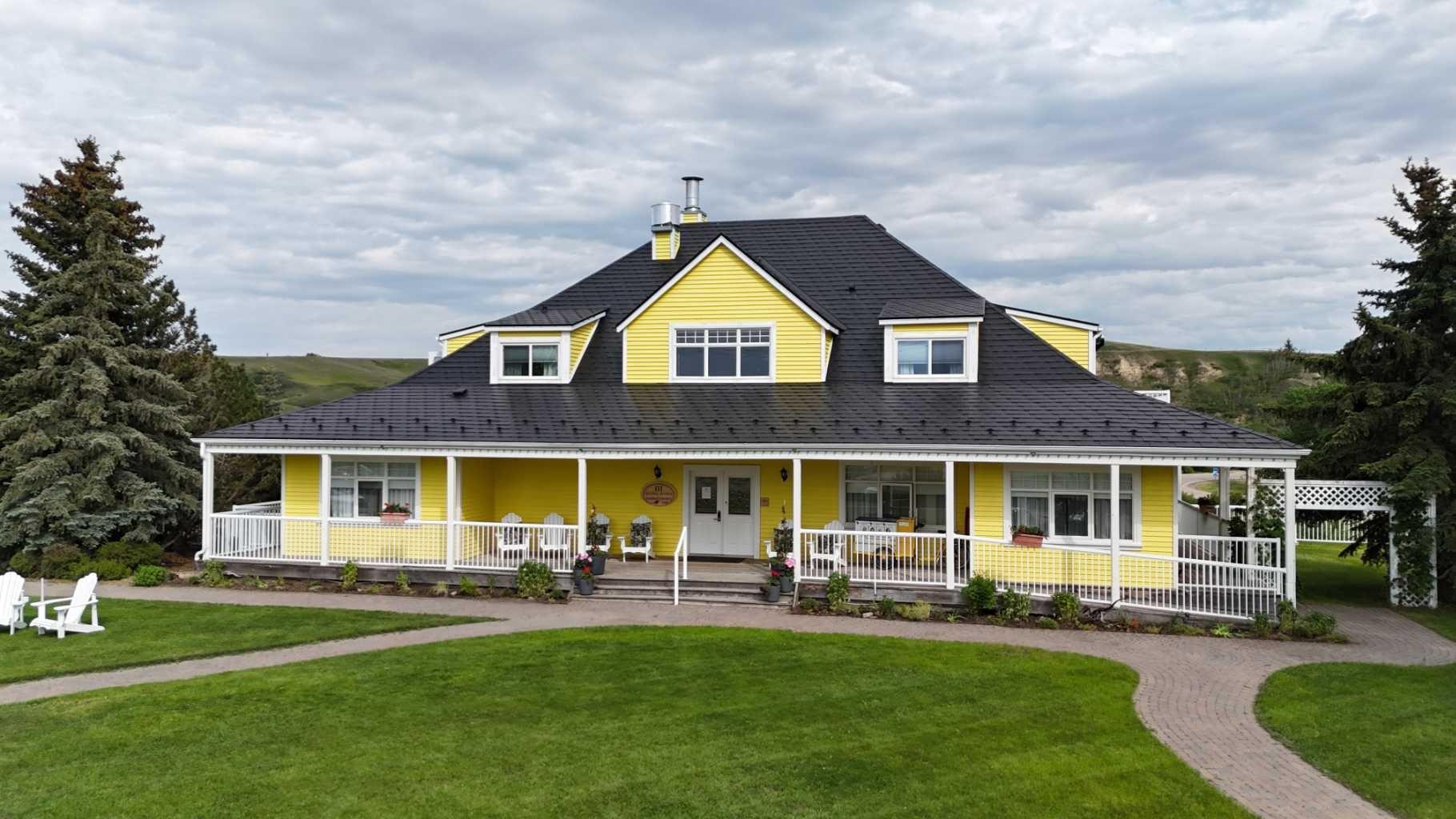 An exceptional opportunity to own a profitable, well-established Bed & Breakfast in Rosebud, one of the province’s most sought-after cultural tourism destinations. The Rosebud Inn is experiencing record occupancy and peak 2025 revenues, driven by a surge in both domestic and international travel to Canada, making this a compelling investment with strong forward momentum.This purpose-built lodge combines warm hospitality, operational efficiency, and guest-focused design, creating a highly rated and repeat-visitor destination. The current owners are committed to a smooth transition and will provide training, offering a true turnkey business opportunity. Set in a scenic valley, the property features attractive cedar siding, a durable metal roof, and expansive land that enhances the guest experience. A welcoming vaulted lobby and reception area create a memorable first impression, while the layout supports both comfort and accessibility. The Inn offers 11 guest rooms, each with a private ensuite bathroom, heated floors, individual climate controls, and air conditioning. Six main-floor rooms are wheelchair accessible with exterior ramp access, while additional rooms are located on the upper and lower levels to provide flexible accommodations. Guests can gather in the bright dining room with seating for 28 and enjoy panoramic views, while the fully equipped kitchen supports a range of culinary offerings. An inviting upper lounge and library provides a comfortable space for relaxation. In total, the property includes 15 bathrooms, ensuring convenience and comfort for all guests. A standout feature is the private owner’s suite on the walk-out lower level, offering two bedrooms, a full kitchen, and a living area with a gas fireplace. Heated floors, a separate entrance, and a private patio create a comfortable and private retreat ideal for owner-operators or on-site management. Additional features include a triple garage, shed, abundant parking with plug-ins, an electric vehicle charger, as well as laundry, mechanical, and storage spaces. Three single family lots also included.Located in the heart of Rosebud, the Inn benefits from steady tourism driven by its renowned arts community, theatre experiences, and peaceful prairie setting. With limited local accommodation supply, the property is well positioned for continued growth. This is a rare opportunity to acquire a high-performing boutique hospitality property in Alberta, offering immediate cash flow, long-term upside, and an ideal blend of investment return and lifestyle.