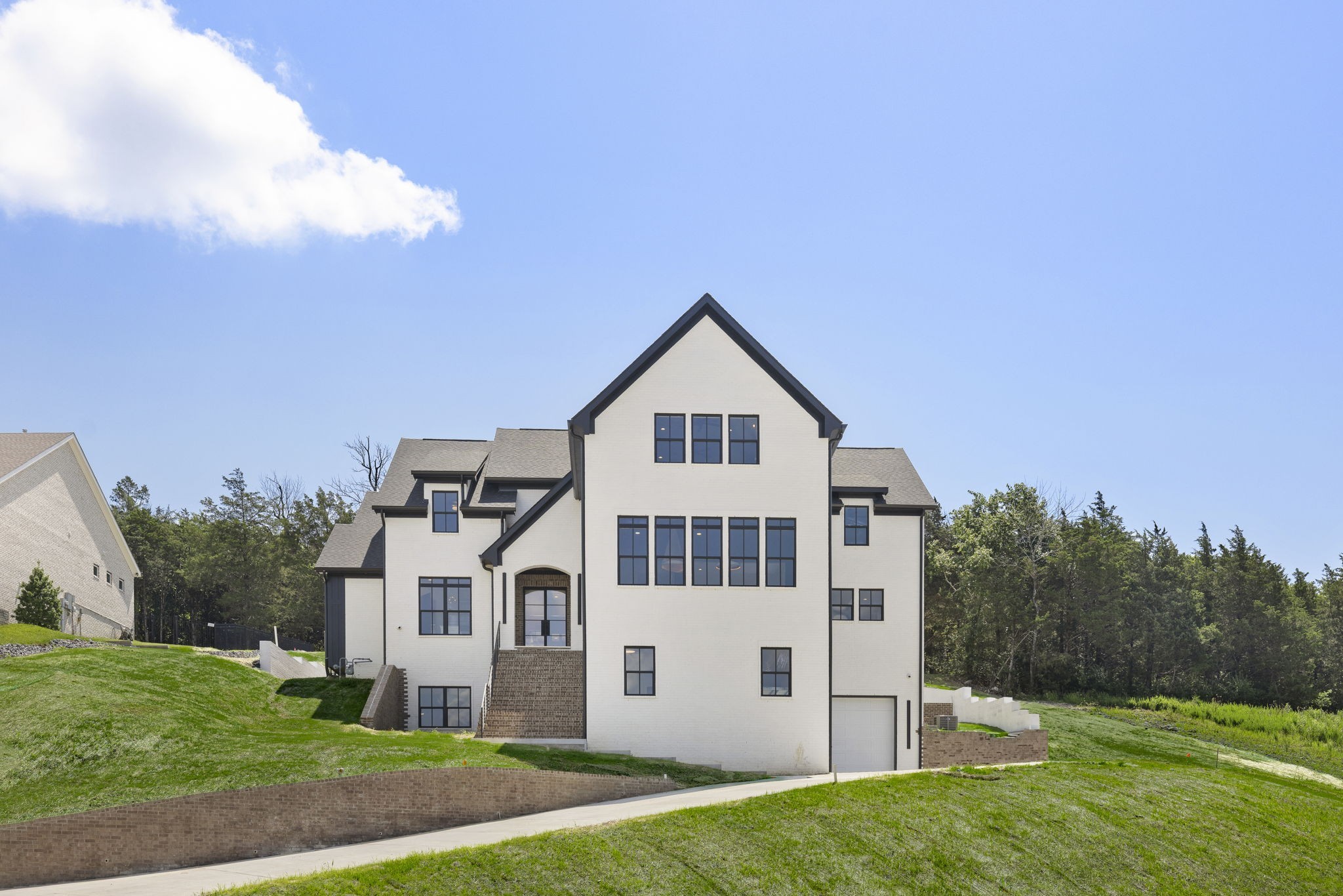 Experience the pinnacle of luxury in this custom-built estate, located in Brentwood’s prestigious Morgan Farms. With breathtaking views of rolling hills and access to top-tier schools, every inch of this residence defines excellence and elegance. Designed for both opulence and entertaining, the open layout features a chef’s kitchen with Miele appliances and a striking soapstone bar complete with an ice maker and refrigerator drawer. The lounge, with its custom fireplace, creates a cozy ambiance, complemented by custom lighting and chandeliers. Downstairs, you will find a second retreat with a full kitchen, just as striking as the first, along with a temperature-controlled wine room. Hidden behind custom millwork, a high-end home theater seamlessly joins a built-in golf simulator for immersive entertainment. Security and technology are unmatched, with a state-of-the-art security system and full CCTV coverage, all centralized in the home’s dedicated electronic server room, delivering peace of mind with sophistication. The primary suite is a beautifully appointed retreat, featuring a vaulted white-oak ceiling, limewashed walls, a spa bath with a soaking tub, dual shower heads, quartzite countertops, heated floors, and a wet bar. Upstairs, discover a spacious bunk room featuring four queen-sized built-in bunk beds, perfect for families and visitors. All interior walls are fully insulated for added privacy and soundproofing. Step outside to a resort-inspired private sanctuary, featuring a heated saltwater pool and hot tub with a sun shelf, surrounded by Travertine decking and artificial turf. Entertain under the covered porch with fireplace and a fully equipped outdoor kitchen—featuring a Korean BBQ grill, gas stove, smokers, and refrigerator. The multiple garages feature soaring 15-foot ceilings, for multiple car lifts, an RV/tour bus bay, and three rapid EV charging stations. This home is a rare offering that seamlessly blends modern indulgence with timeless design.