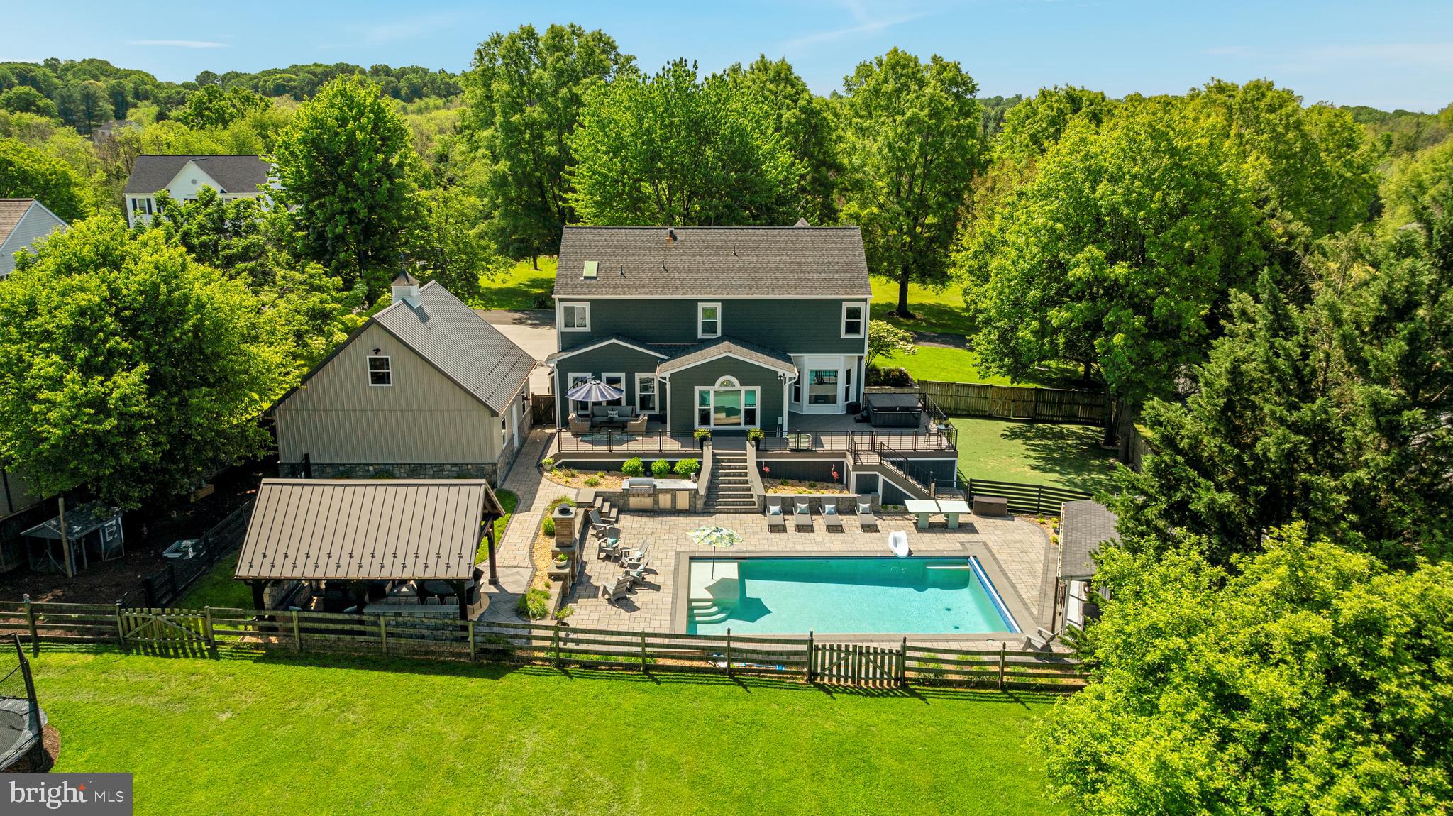 If your wish list has ever felt a little unrealistic, this home is where things start to line up. 37440 Whitacre Lane is the rare kind of property that gives you the breathing room, privacy, and lifestyle you want without asking you to maintain the acreage you don’t need. Set on just under an acre, yet backed by access to 21+ acres of shared green space, including a fishing pond, barn, and more, this home lives far larger than its footprint. You get the feeling of space and separation, the kind that’s hard to find, with a backyard designed to be enjoyed, not managed. It is the balance most homes promise, but very few actually deliver.37440 Whitacre Lane is a refined retreat in the heart of the Telegraph Springs community, about as close to downtown Purcellville as you can get without paying extra taxes. With 4 bedrooms and 3.5 bathrooms, the home has been meticulously transformed through a series of high-end upgrades that blend editorial-style aesthetics with functional luxury. Every detail has been curated for the discerning homeowner. The exterior makes a strong first impression with a massive detached garage, oversized concrete driveway, and a modern front porch.  Inside, the home carries that same intentionality. New flooring spans all three levels, paired with fresh 2026 paint and updated lighting that brings a clean, cohesive feel throughout. The kitchen is positioned at the center of daily life, opening seamlessly into both the sunroom and living room, so the space feels connected whether you are hosting or just moving through your day. It is designed to keep up with real life while still delivering a polished look, featuring quartz countertops and a well-timed suite of appliances, including a 2023 refrigerator and microwave, a 2020 dishwasher, and a 2014 cooktop.At the front of the home, both the sitting room and the music room offer flexibility that is hard to find. Each space can easily function as a private office or flex room, with French doors in place and the option to enclose either room in the future as needed. Upstairs, the spacious primary suite features a 2026 bathroom update and a fully remodeled secondary bathroom.  The lower level adds versatility with a remodeled 2025 full bath, a bonus room, and direct outdoor access to the fenced K9 turf area.  This space could function as an au pair or in-law suite for someone looking for separate living spaces.  The K9 turf area deserves more attention for its functionality!  Imagine your dogs coming in from the rainiest of days without muddy footprints.  A lawn you don’t have to mow or try to keep in place that is designed to drain itself, and can be sprayed down. The backyard is where this property separates itself. The 20x36 saltwater heated pool with a tanning ledge is the centerpiece, surrounded by Techo-Bloc hardscaping and natural stone work that gives the space weight and permanence. Enjoy controlling your pool cover, lighting, and heaters all through an app for maximum convenience.  A 14x20 Amish-built pavilion extends the usability of the space well beyond summer, complete with a gas fireplace, power, ceiling fan, and TV hookups. Add in the outdoor kitchenette, firepit, and surround sound, and you have a setup that is ready for everything from quiet evenings to full gatherings. The 2025 deck frames the space perfectly with metal railings, custom lighting, and rounds it out with practical upgrades that make daily life easier. A dedicated K9 turf area adds thoughtful function to the backyard, giving pets their own easy-care space while helping keep the rest of the yard clean, usable, and ready for entertaining. The detached garage and loft add another layer of flexibility. Complete with spray foam insulation, fiberglass doors, and a massive built-in Toolchest storage, the main level functions as a true workspace. Above, the loft office is a separate, quiet environment with its own HVAC and hardwired internet, ideal for a creative space or lounge.