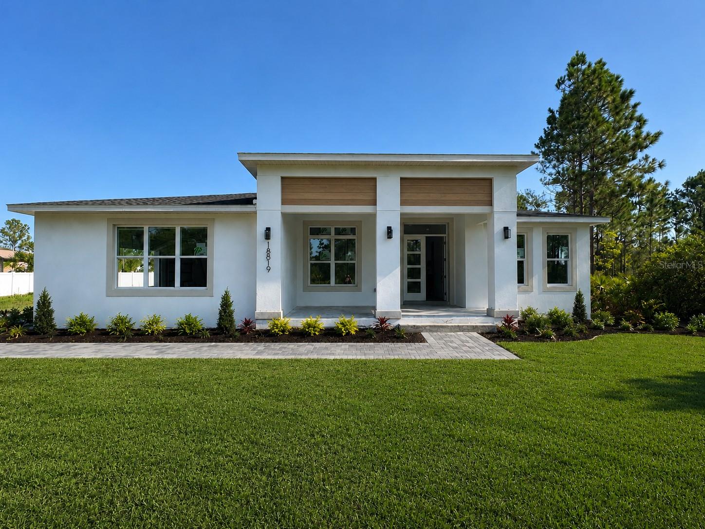 Under Construction. Peaceful country living yet with full infrastructure, and easy connectivity - just minutes to the 408 and close to the airport, beaches, shopping, UCF, and the Space Coast, all from a quiet side street tucked away from the busier corridors nearby. Step inside this newly built home and you'll see an epic open floor plan anchored by a huge great room concept with electric fire place & luxury vinyl plank flooring throughout, a chef-inspired kitchen featuring two-tone cabinetry, a blonde wood-cased island with bar seating, a large built-in pantry, built-in oven, stainless appliances, cooktop, and a range hood vented to the exterior, complemented by a stunning arched dry bar with floating shelves, a wine fridge, and designer backsplash. A versatile front office adds flexibility, while one of the four guest bedrooms offers the option to convert into a private suite. Retreat to the oversized primary bedroom boasting his-and-hers walk-in closets with custom closet systems and a spa-inspired bath with a wet-room-style tub and shower combination, plus an indoor laundry room with abundant storage. Outside, enjoy a pavered front porch and huge pavered back patio overlooking a sprawling backyard surrounded by lush Florida vegetation ideal for future hiking trails, birdwatching, and wildlife viewing. There is room for a future pool and the home is already pre-wired for a pool and summer kitchen addition. Additional highlights include an oversized three-car garage with EV charging infrastructure already in place, dual well pumps — one for irrigation & one whole-home system with complete filtration and water treatment — this is a rare opportunity to own a newly built, thoughtfully designed property that blends modern & classic design with timeless comfort in one of Orlando's most connected country-living communities. Photos are virtually staged.