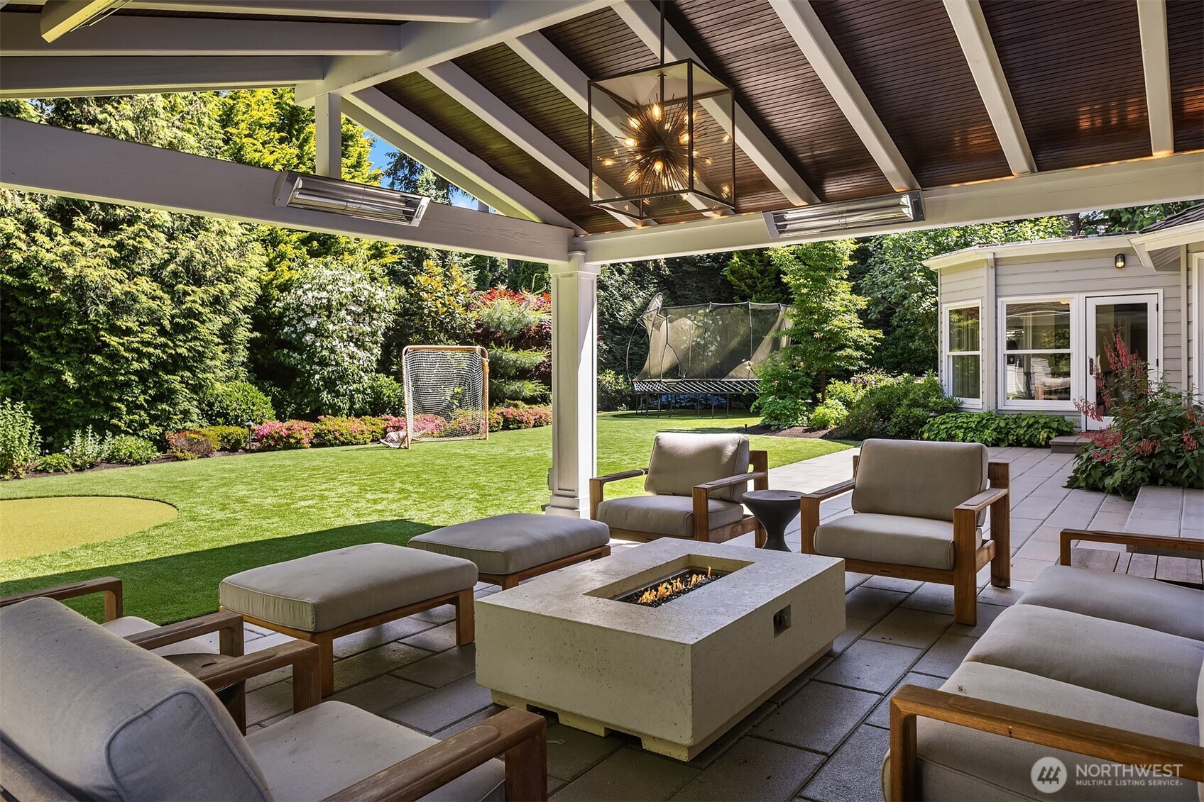 Covered backyard area centers on a fire table with views to the putting green