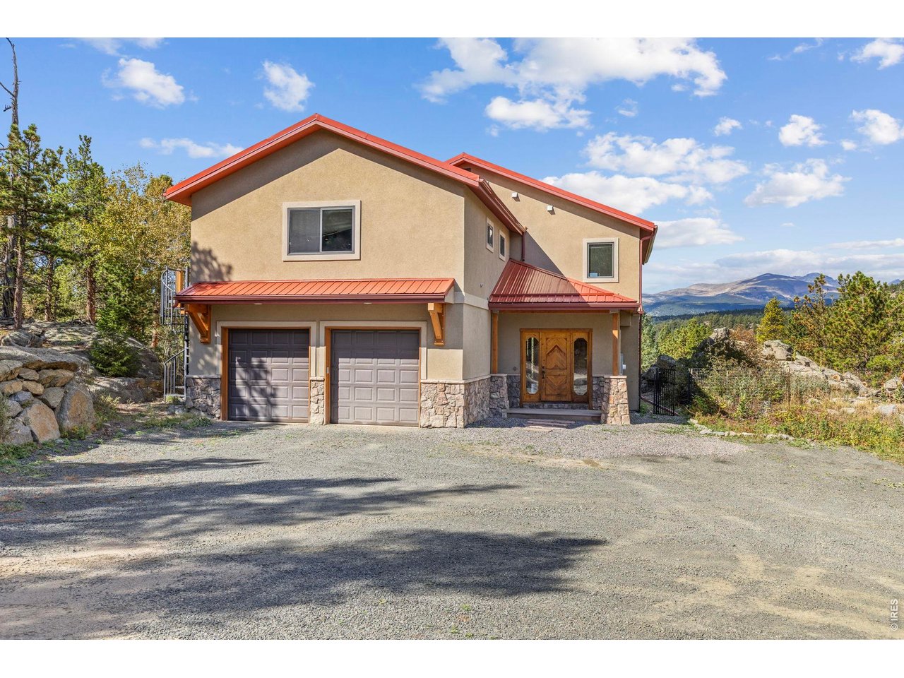 Located at the end of the road, this custom stucco home, built in 2007, occupies 7 private acres in a coveted neighborhood just minutes from Nederland, with 3 sides adjoining National Forest. Framed by dramatic rock outcroppings and sweeping snowcapped Indian Peaks views, this exceptional property offers refined craftsmanship, seclusion and direct access to nature. A private drive leads to a level parking area and oversized 2-car garage. Inside, the tiled foyer opens to an inviting open-concept main level designed for living and entertaining. The well-appointed kitchen features granite counters, a 4-person bar, stainless appliances and an oversized pantry, while the adjacent dining and living areas showcase newly refinished hickory floors, tall ceilings and a wall of windows capturing the mountain panorama. Step outside to a spacious composite deck and flagstone patio that leads to a hot tub nestled against tumbled boulders. A dedicated office with Murphy bed offers flexibility as a 4th bedroom, while a half bath completes the main level. Upstairs, 3 generous bedrooms accompany a massive rec room/flex space with balcony, views and a metal spiral staircase to the grounds. The primary suite is oriented toward the views and features an ensuite with soaking tub, separate shower and private balcony with spiral stairs to the deck. An owned solar system helps offset energy costs. A fenced yard provides space for pets or play, while rock outcroppings and a private trail system lead toward National Forest and miles of hiking from your doorstep. The basement offers potential for future finished space, with a finished laundry room already in place. A metal roof and new tankless water heater add to the home's enduring appeal. Just 10 minutes to Nederland and an easy, scenic commute to Boulder via the summer access road, this is a special mountain property with the quality, setting and timeless appeal to become a legacy home for generations.