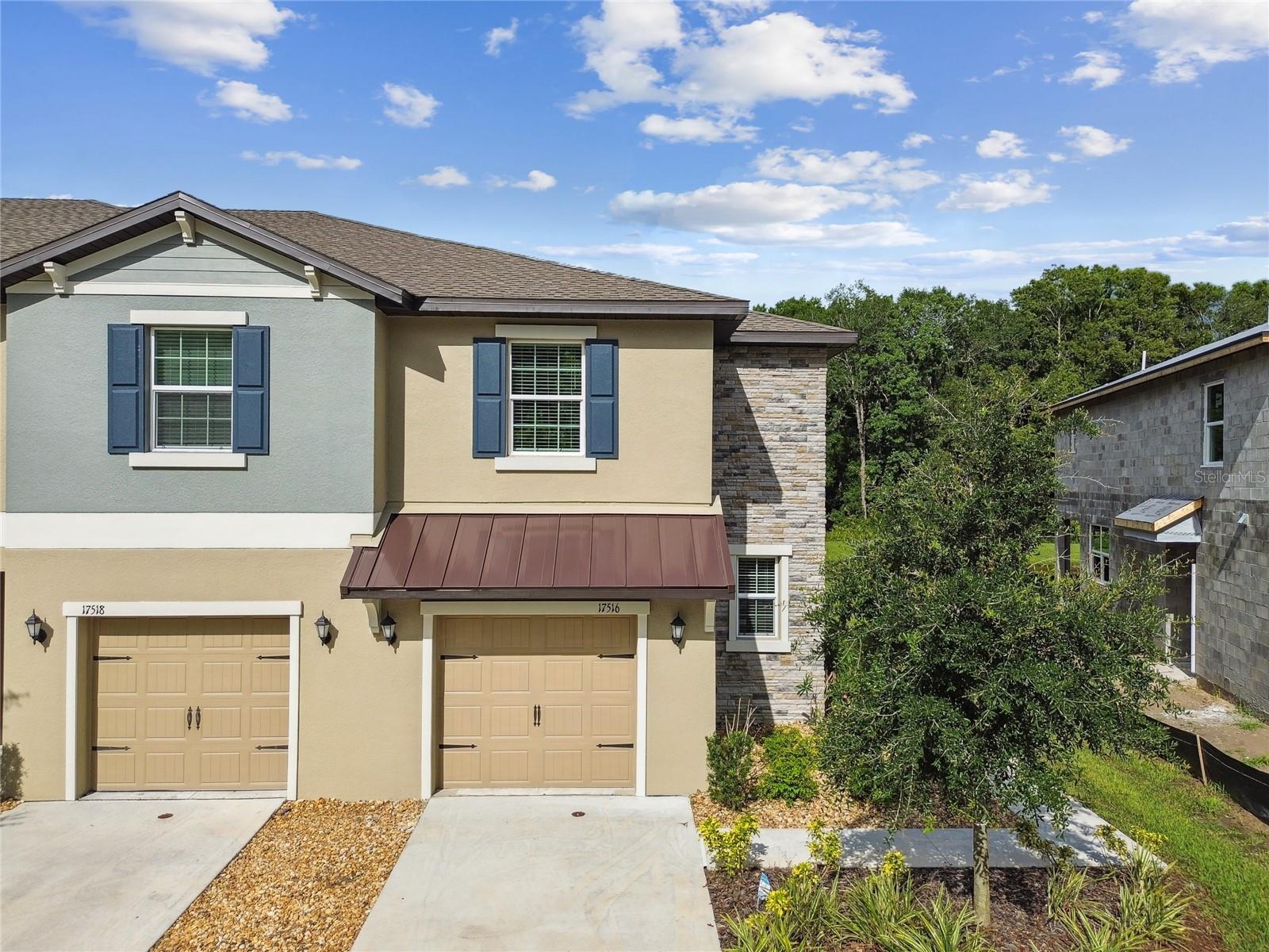 NEVER LIVED IN-FORMER SALES MODEL END UNIT Townhome located in the highly desirable new master-planned community of ANGELINE and showcases a host of stylish upgrades throughout. The popular ST. KITTS FLOORPLAN by Lennar features TILE FLOORING on the entire first floor, an open-concept layout, and thoughtfully designed living spaces. Just off the foyer is a convenient DROP STATION, perfect for organizing daily essentials. The kitchen is equipped with GRANITE COUNTERS, STAINLESS STEEL APPLIANCES, and modern cabinetry, all overlooking the spacious great room with a DECORATIVE ACCENT WALL and upgraded lighting and ceiling fans. Step out back to enjoy the SCREENED AND COVERED LANAI with peaceful views of CONSERVATION and a POND. Upstairs, the PRIMARY SUITE offers ON-TREND WALLPAPER ACCENTS, a large WALK-IN CLOSET, and a private ENSUITE BATH with a DUAL SINK VANITY and WALK-IN SHOWER featuring SUBWAY TILE. Two additional bedrooms share a JACK-N-JILL STYLE BATHROOM, while a large LOFT provides flexibility for a HOME OFFICE, PLAYROOM, or SITTING AREA. The second-floor LAUNDRY ROOM is spacious and ideally located near the bedrooms for added convenience. As part of ANGELINE, residents will enjoy a thoughtfully designed 6,200-ACRE MASTER-PLANNED COMMUNITY centered around modern living, innovation, and wellness. Future amenities include a CRYSTAL LAGOON, a vibrant TOWN CENTER with shopping and dining, over 3,600 ACRES OF GREEN SPACE, and 100 MILES OF PLANNED TRAILS. ANGELINE is home to the STEM-FOCUSED ANGELINE ACADEMY OF INNOVATION and a 775-ACRE LIFE SCIENCES HUB led by MOFFITT CANCER CENTER. Outdoor enthusiasts will appreciate the COMMUNITY FARM, regional park, and extensive recreational areas throughout the development. Ideally located with easy access to the SUNCOAST PARKWAY, this home offers a convenient commute to TAMPA INTERNATIONAL AIRPORT in 25 minutes, DOWNTOWN TAMPA in 40 minutes, and some of FLORIDA’S TOP BEACHES.
