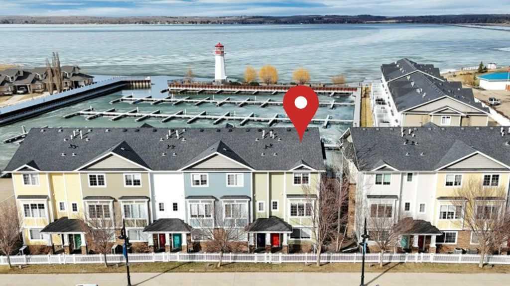FULLY FURNISHED | END UNIT | WATERFRONT | GATED MARINA COMMUNITY ~ Welcome to a rare turn-key opportunity in Sylvan Lake—a fully furnished, end-unit townhome in the sought-after WatersEdge Marina development. This former show home combines premium location, added privacy, and immediate usability with no setup required. ~ The end-unit position is a major advantage—offering additional windows, more natural light, and fewer shared walls. The result is a brighter, quieter home that feels noticeably more open than interior units. ~ The main living space features an open-concept design with large windows capturing panoramic views of the marina and lake. The kitchen is bright and functional with white cabinetry, granite countertops, a central island, and stainless steel appliances, now upgraded with a brand new induction stove. Fresh new paint throughout gives the home a clean, modern feel. The dining and living areas flow seamlessly to the private deck—ideal for taking in sunsets and the lakefront atmosphere. ~ Upstairs offers a well-designed layout with a spacious primary suite complete with walk-in closet and private ensuite, plus two additional bedrooms, a full 4-piece bathroom, and convenient upper-floor laundry. ~ The heated, double-length garage is a standout feature—finished with high-grade flooring, hot and cold taps, and a dedicated storage/utility area, providing both function and flexibility for year-round use. ~ Additional features include central A/C, built-in sound system, central vacuum, and quality window coverings—all included. ~ Located in the gated WatersEdge Marina community, this home offers one of the most desirable lakefront settings in Sylvan Lake. Just steps to the marina, beach, lighthouse promenade, and downtown core—walk to restaurants, shops, and the seasonal farmers market with ease. ~ Enjoy true lakefront living with panoramic views and direct access to Sylvan Lake’s vibrant lifestyle—morning coffee by the water, afternoons on the beach, and evenings watching the sunset from your deck. ~ With both short-term and long-term rentals permitted, this property also provides flexibility for personal use or income potential. ~ Fully furnished. End unit. Turn-key. Premium location. This is a stronger package than typical offerings in the complex—and it shows the moment you walk in.