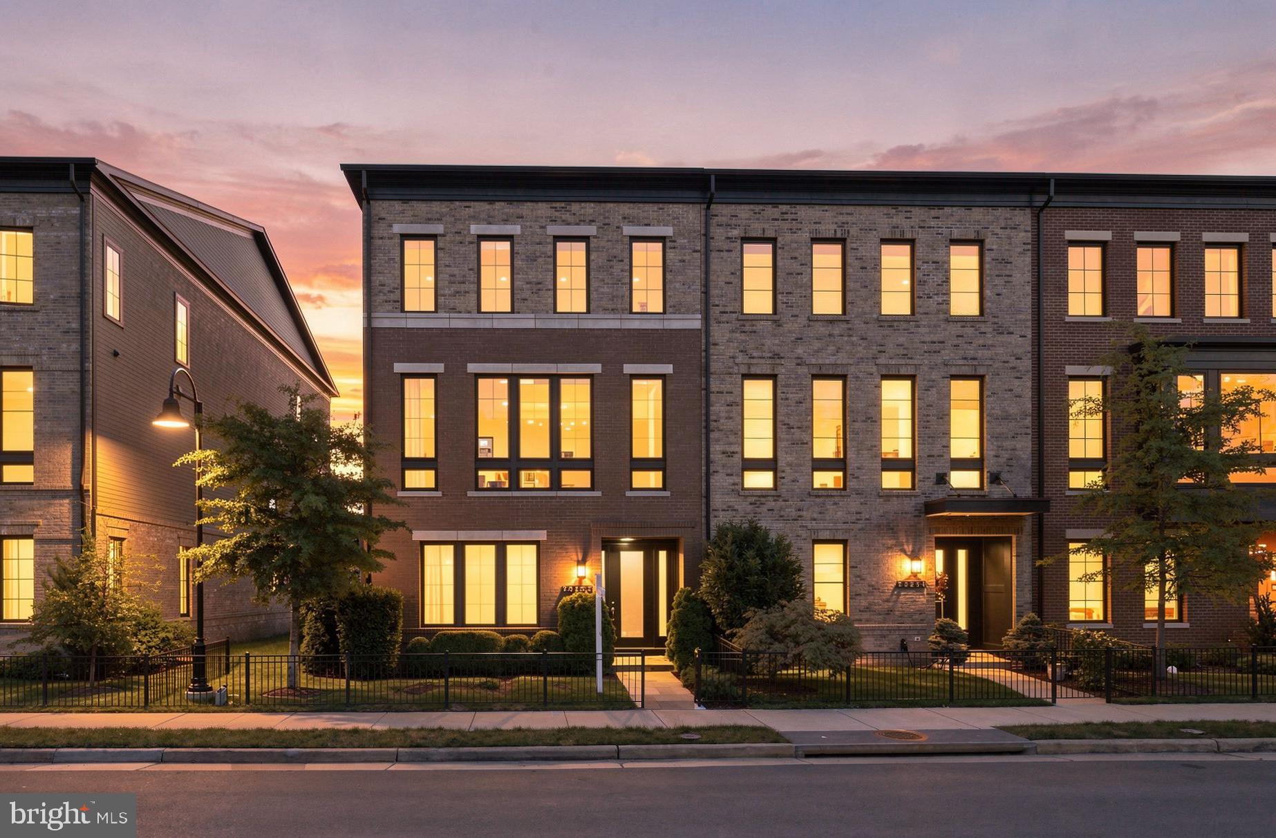 Welcome to this beautifully upgraded Miller & Smith Uptown townhome, an impressive 24-foot-wide layout offering nearly 3,300 square feet of thoughtfully designed living space in the heart of One Loudoun. What truly sets this home apart is its setting: the front overlooks a peaceful, wooded section of Central Park, while the rear opens to a landscaped community green space with a firepit and gathering area. It offers a rare sense of openness and privacy while keeping you just steps from everything One Loudoun has to offer. | From the moment you enter, the home's generous scale and thoughtful design are immediately apparent. The entry level features a spacious room with a closet and full en-suite bath, offering exceptional flexibility as a guest suite, home office, or private retreat. A second space nearby provides a convenient mudroom or office area. This level also offers direct access to the finished two-car garage, complete with epoxy flooring and a garage storage system. | Throughout the home, thoughtful upgrades add both style and function, including modern stair railings and custom motorized blinds on every window. The main living level is bright and expansive, with 10-foot ceilings and wide-plank engineered wood flooring. The family room centers around a striking gas fireplace with a custom tile surround, while wood ceiling beams and an oversized ceiling fan add warmth and architectural interest. A large sliding glass door opens to the covered terrace, creating an effortless connection between the indoor living space and the outdoors. The kitchen is designed equally well for everyday living and entertaining, with an oversized quartz island, upgraded cabinetry, stylish tile backsplash, and a professional 6-burner gas range with hood. GE Café appliances include a wall oven, microwave, French-door refrigerator, and dishwasher. A dedicated coffee and beverage station with built-in drink cooler adds an especially thoughtful touch. The adjacent dining area features a tray ceiling, and a powder room completes this level. | Upstairs, the primary suite offers a quiet retreat with a tray ceiling, ceiling fan, and two custom walk-in closets. The en-suite bath features a dual-sink vanity, tiled walk-in shower, and separate water closet. Two additional bedrooms provide flexibility for family, guests, or a home office, with one offering its own private bath and the other located just steps from the hall bath. A dedicated laundry room with front-loading washer and dryer completes the upper level. | Living in One Loudoun means having an exceptional collection of amenities and conveniences right outside your door. Residents enjoy a private clubhouse, outdoor pool, tennis and pickleball courts, playgrounds, walking paths, dog parks, open fields, a pond with fountains, and an outdoor amphitheater. Just a short walk away, the One Loudoun retail and dining district offers an impressive mix of restaurants, boutiques, entertainment, fitness, and everyday conveniences, including Eddie Merlot's, Lost Fox, Matchbox, Uncle Julio's, Lululemon, Arhaus, Pottery Barn, Trader Joe's, and Alamo Drafthouse Cinema. Seasonal events and farmers markets add even more to the community's vibrant, walkable lifestyle. For commuters, Route 7, Loudoun County Parkway, the Silver Line Metro, Dulles International Airport, and Washington, DC are all within easy reach. | With its wide floor plan, exceptional scale, thoughtful upgrades, beautiful views, and unbeatable walkability, this is a home that offers both the comfort of a beautifully finished residence and the lifestyle that makes One Loudoun so special.
