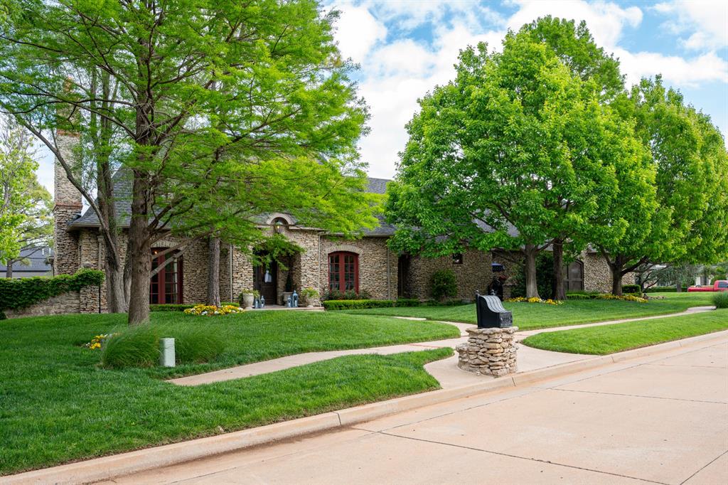Offering a rare combination of privacy, luxury, and designer-curated finishes, this custom estate home is situated on an oversized corner lot backing to a scenic greenbelt. At the heart of the home, the gourmet kitchen is beautifully appointed with custom cabinetry, marble countertops and backsplash, a farmhouse sink, upgraded vent hood, 6-burner Viking range, Bosch dishwasher, walk-in pantry, and a large island that opens seamlessly to the great room. Anchored by a stone fireplace and custom built-ins, the great room provides an inviting gathering space. A formal dining room highlights designer chinoiserie wallcoverings and a statement chandelier, while the dedicated study offers a sophisticated retreat with leather ceiling details, exposed beams, a stone fireplace, and custom wood doors. The primary suite is conveniently located on the main level and offers direct access to the patio. Its spa-inspired bath includes a tumbled marble walk-in shower with dual shower heads, whirlpool tub, marble flooring, and granite vanities. Upstairs, you'll find versatile secondary suites, including a game room suite, guest suite, and an additional bedroom with a private en suite bath and access to a finished attic storage area. Designed to maximize both indoor and outdoor living, the property features covered front and back porches, updated flagstone patios, a private side courtyard, refreshed landscaping, and a private security gate leading to the residence and motor court. Mixed stone, wrought iron, and wood fencing enhance the property's character, while scenic greenbelt views provide a peaceful backdrop. Additional designer details include handpainted tile, custom-painted vanities, wrought iron chandeliers, and numerous custom finishes throughout. This meticulously maintained luxury home offers an exceptional blend of elegance, privacy, and refined living.