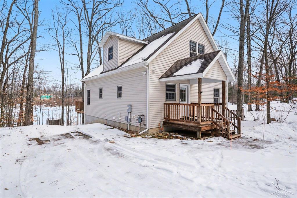 Wake up to breathtaking waterfront views in this stunning, fully updated home on beautiful ALL SPORTS Perch Lake. With 5 bedrooms ~ 3 full baths and over 2,500 sq ft of living space this spacious retreat offers the perfect blend of cozy cottage and lakeside charm. Step inside to an inviting open-concept main level featuring rich wood floors, maple cabinetry, solid surface countertops, and a large center island-ideal for gathering with family and friends. The dining and living areas flow seamlessly together, highlighted by a cozy wood stove and a dramatic wall of windows with double sliding doors that frame spectacular lake views and fill the home with natural light. Step out onto the oversized deck to enjoy the up north wooded atmosphere, relax, entertain, and enjoy peaceful mornings or sunset evenings overlooking the lake and private beach. Upstairs, you'll find two large bedrooms and a full bath, including a serene primary-style retreat with a custom white shiplap vaulted ceiling, walk in closet and picturesque lake views-your own private escape. The newly finished walkout lower level expands your living space with a generous family room, a charming nook tucked under the stairs, two additional large bedrooms, and a full bath-perfect for guests, a home office, or multi-generational living. The lower level  has a walk out basement with sliding glass door that leads to the brick patio under the first floor deck. Outside and to the front, there is a spacious 30'x 40' pole barn for all your toys! Built in 2017, it has concrete flooring, 3 garage access doors and 100 amp electrical service. On the lakeside, you have 70' of frontage with a large sandy beach, an 8'x8' shed and a new platform dock to tie your 'toon up to or simply cast your fishing line! One last bonus, this home has natural gas and central air! Whether you're looking for a year-round residence, rental investment or the ultimate lakefront getaway, the exceptional Perch Lake property offers space, style, and stunning views in every season. Schedule your