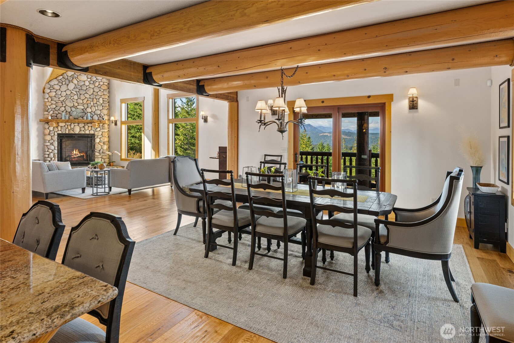 Spacious dining area with exposed log beams, hardwood floors, and direct access to one of the home’s four porches.