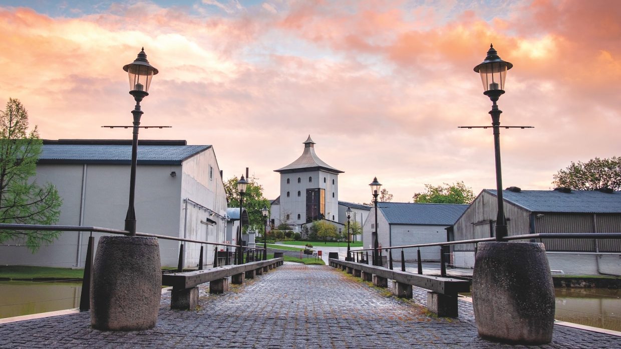 As the sun sets over James Sedgwick Distillery in South Africa, the sky is pastel pink, orange, and blue.