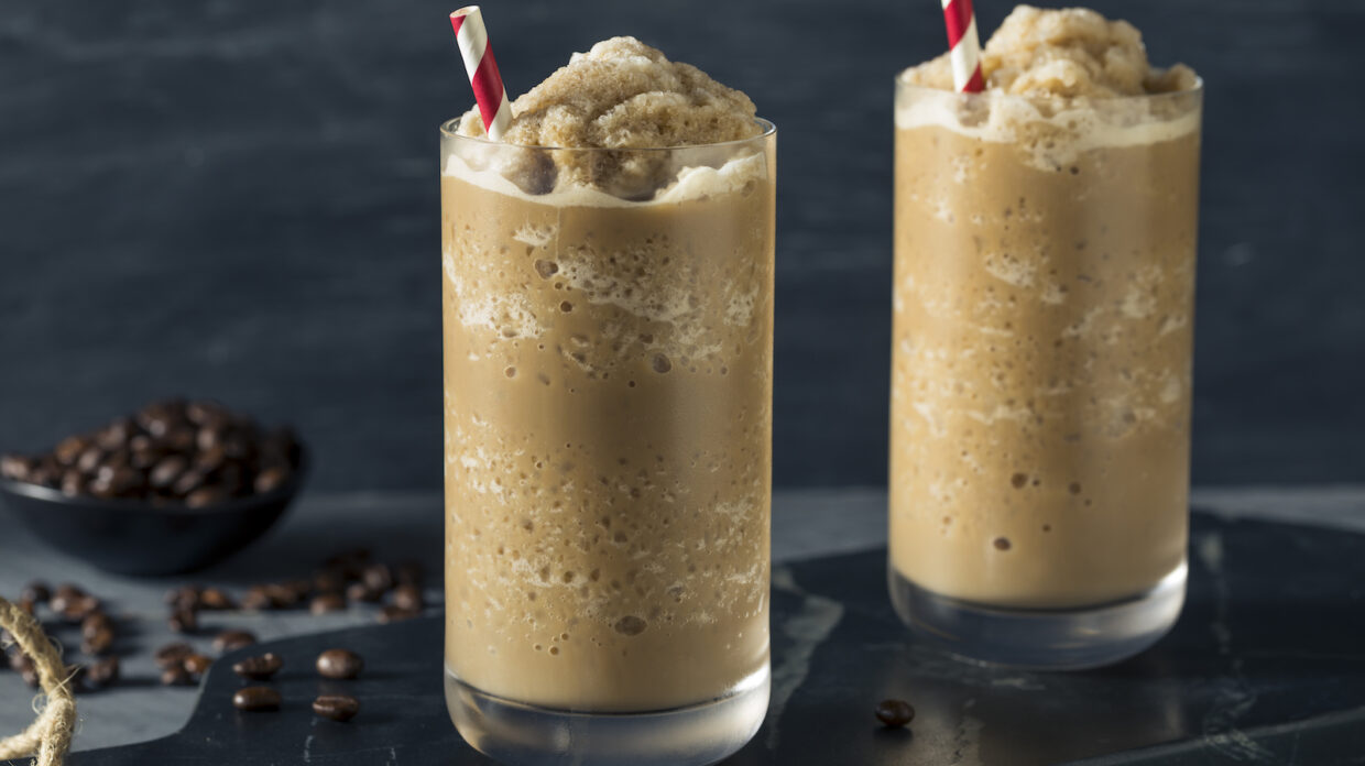 Two frozen coffee drinks sit in front of some coffee beans.
