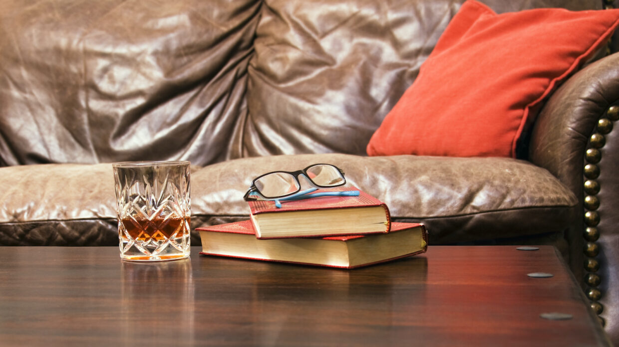 a relaxing scene two books with a pair of glasses and a crystal whisky glass