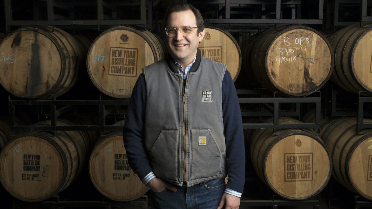 Allen Katz stands in front of several whiskey barrels.