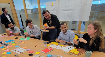 Rider Lab team members sit at a conference table and use post it notes to organize their ideas