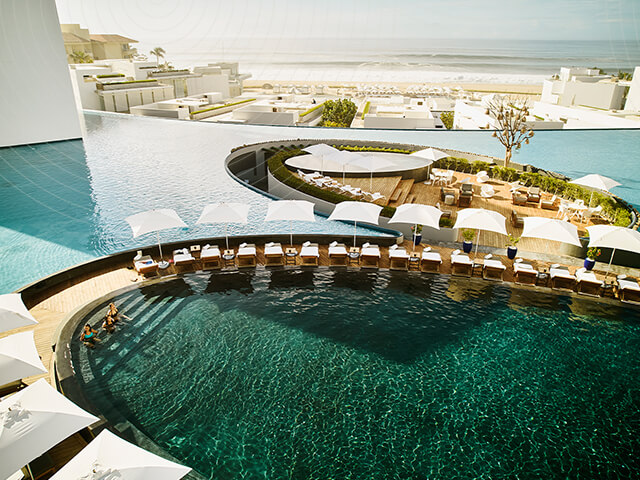 A serene poolside view of a hotel with a lake in the background at dawn.
