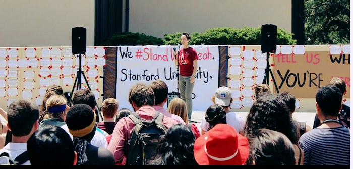 A rally for #standwithleah at Stanford. A student addresses a gathering, holding a microphone.