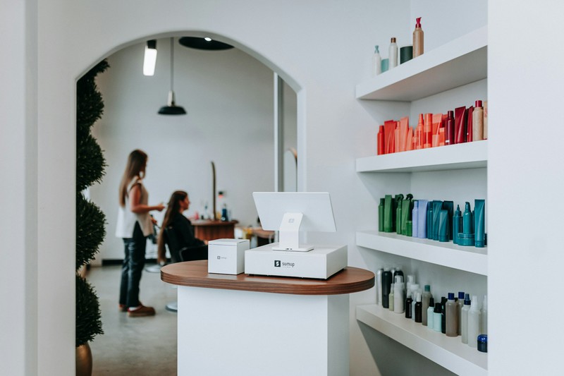 Hair salon interior with styling stations, products on shelves, and clients in chairs