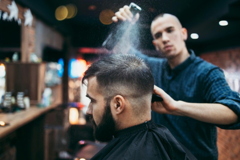 Barber spraying a client's hair with water while finishing a fade