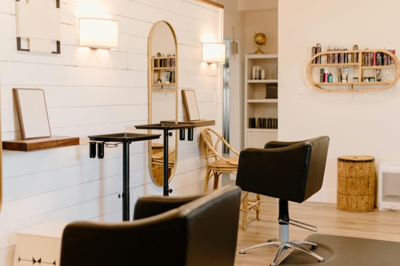 Empty salon styling stations with chairs, mirrors and product shelves