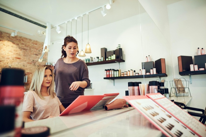 Stylist showing a client hair color swatch books at a salon counter