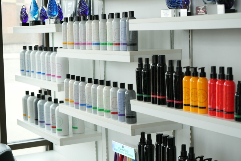 Rows of retail hair care bottles arranged on white salon shelves