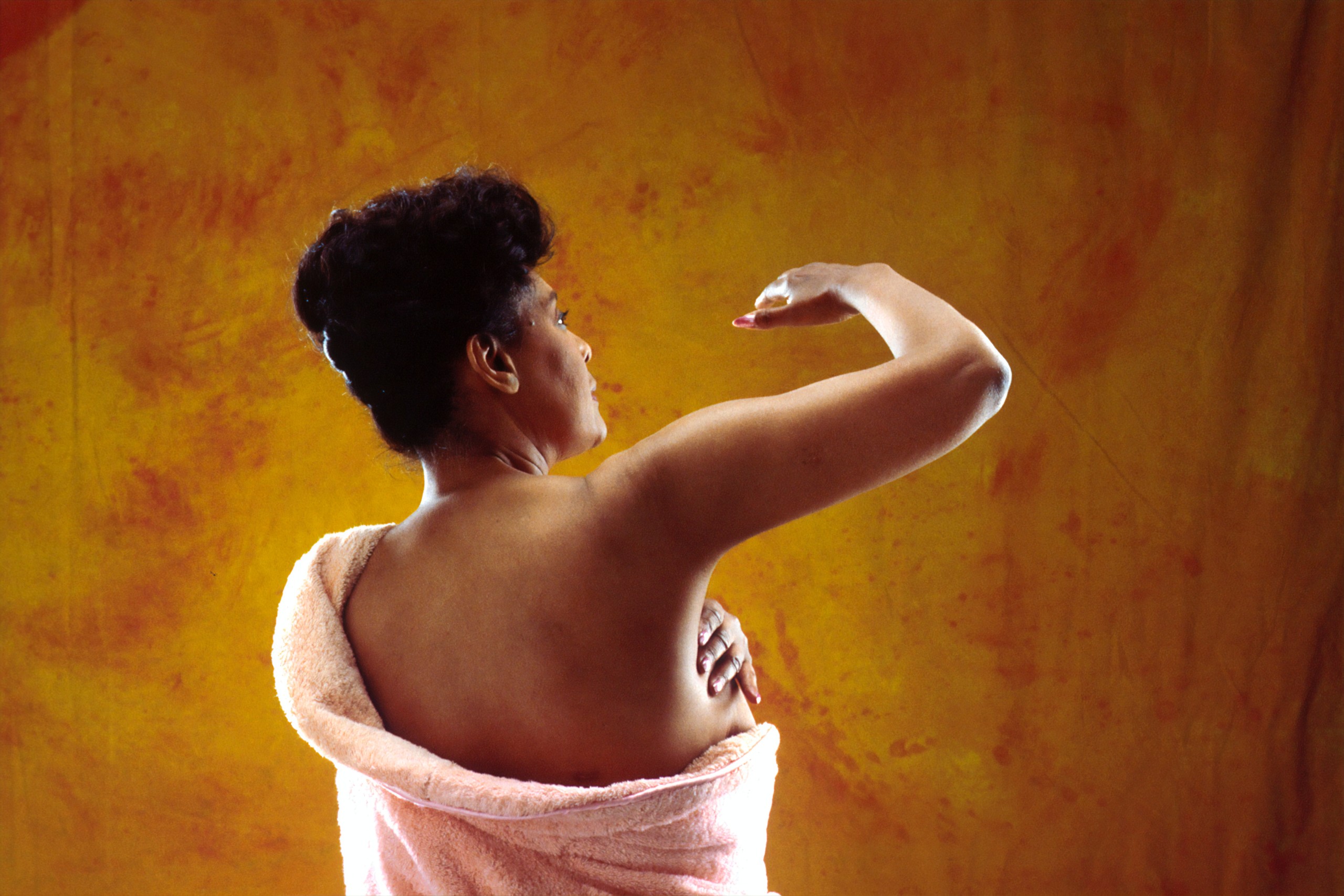 Rear-facing woman completes a breast self-examination