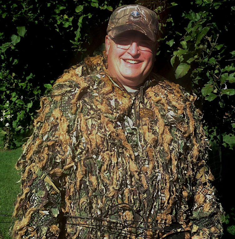 A portrait of a hunter in camouflage gear.