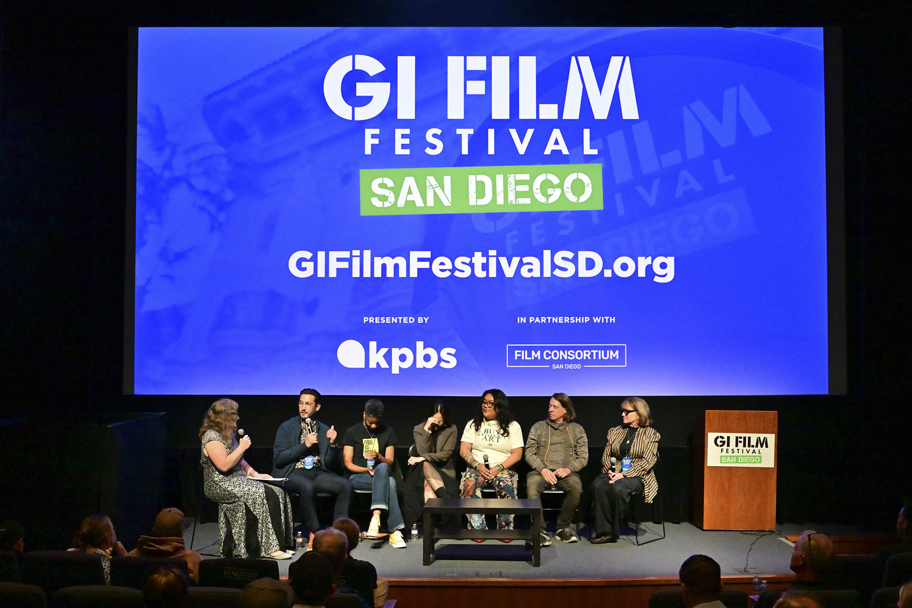 Panelists on stage with GI Film Festival graphic behind them