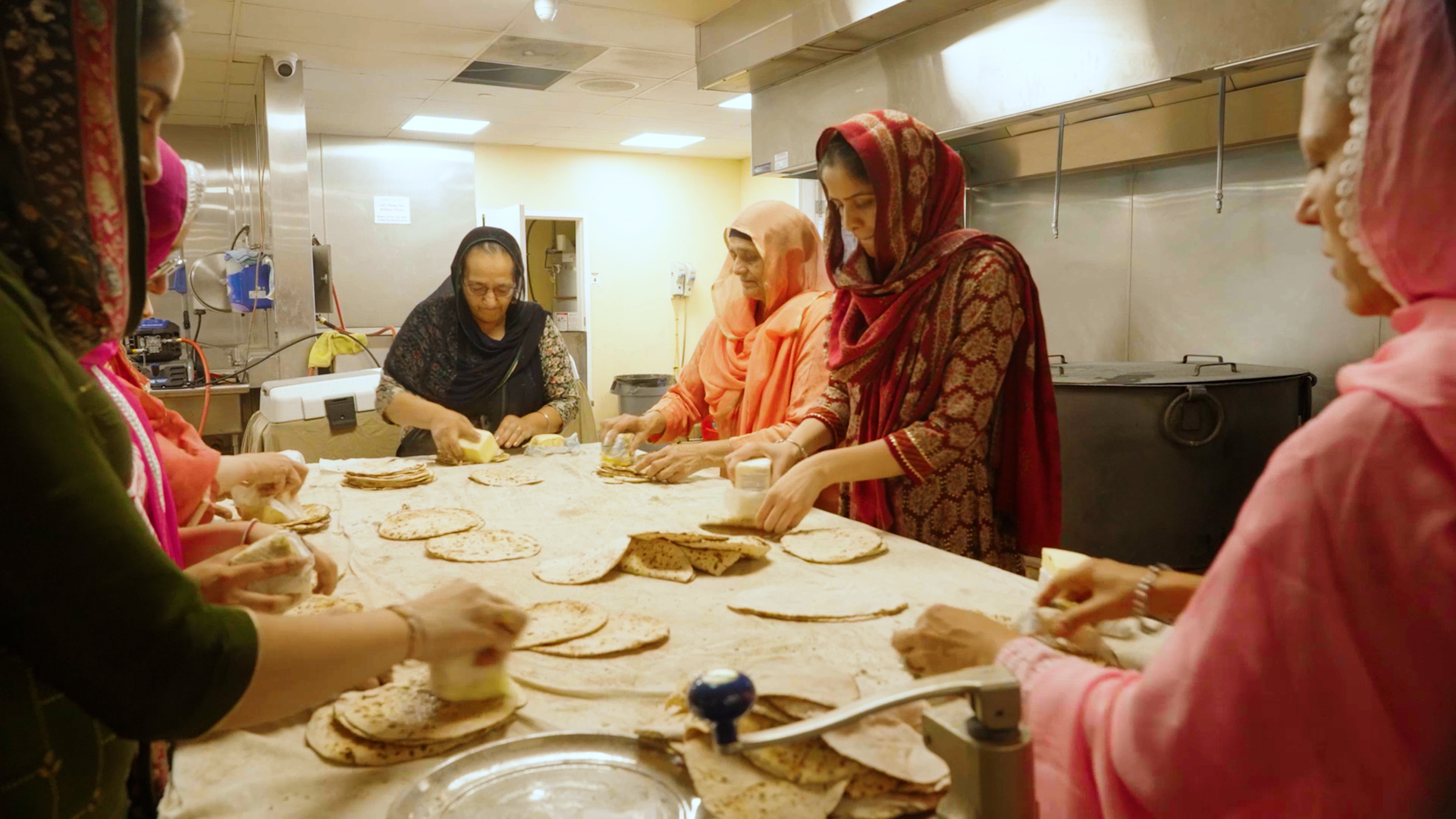 brown skinned women with headscarves making bread