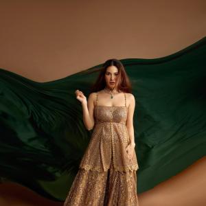 Elegant Golden Sequined Dress with Green Backdrop - Fashion Photoshoot