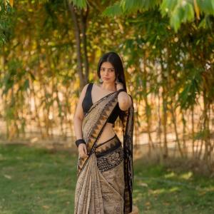 Actress bandhavi sridhar in a traditional black and beige saree look outdoors