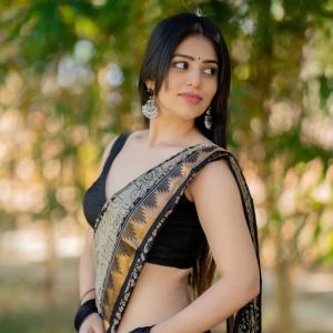 Actress bandhavi sridhar in a traditional black and beige saree look outdoors