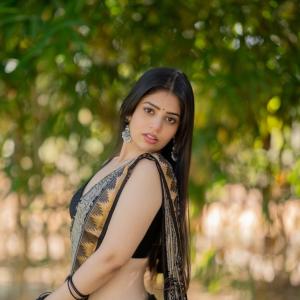 Actress bandhavi sridhar in a traditional black and beige saree look outdoors