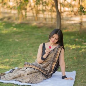 Actress bandhavi sridhar in a traditional black and beige saree look outdoors