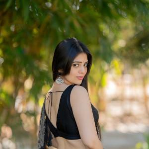 Actress bandhavi sridhar in a traditional black and beige saree look outdoors