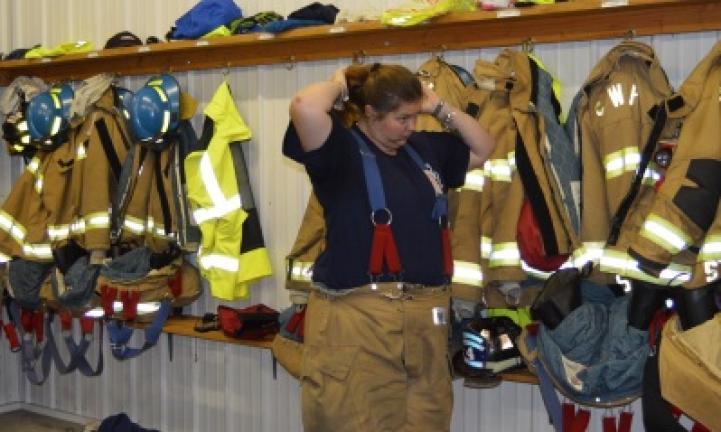 Firefighter Kayla Hartz begins the process of putting on turnout gear, which is a great equalizer.
