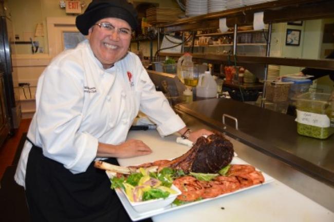 Chef Z with her tomahawk steak served with a side of Chimichurri sauce, sauteed fingerling potatoes, and a vegetable blend of yellow squash, shallots and kale.