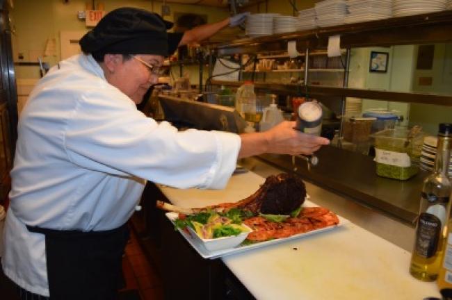 Rivera adds a final squeeze of balsamic glaze to the sliced tomatoes before the steak is served.