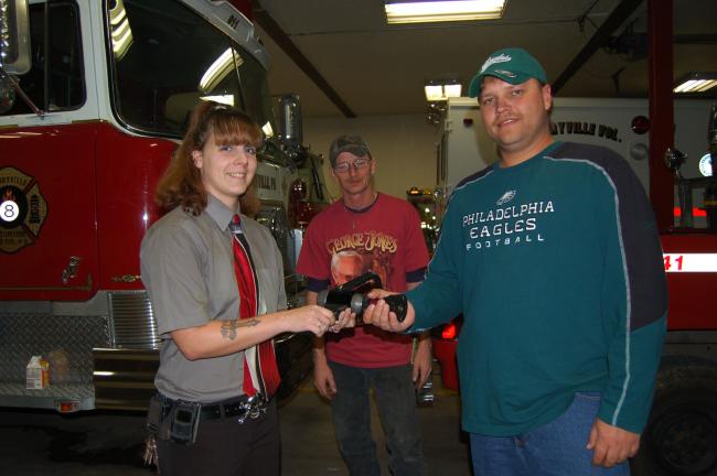Danny Keiser, right, accepts a fire hose nozzle from Christina O'Brecht of Palmerton. O'Brecht is a member of Crusaders for a Cause, a non profit fundraising organization which raises funds for local needs in the community. Art Strohl is standing in…