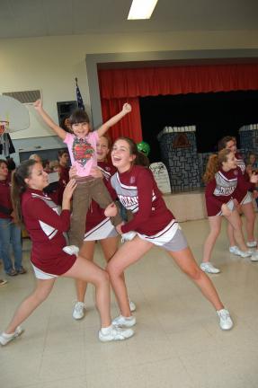 Gail Maholick/TIMES NEWS Lehighton High School cheerleaders Megan Turpin, Sydney Schafer and Haley Sawyer give Gianna Heller a taste of cheer leading during a pep rally held at Franklin Elementary School.